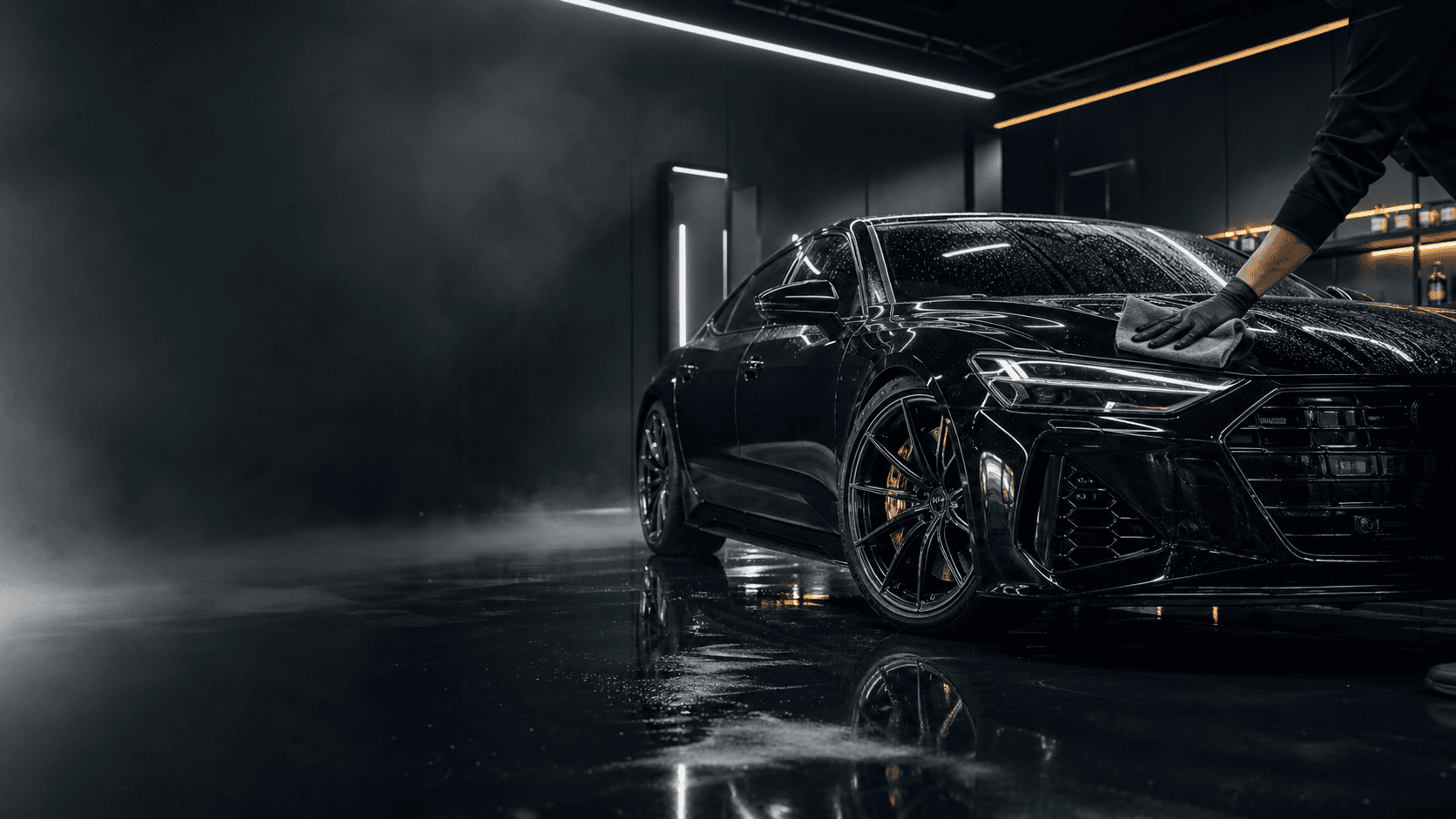 Luxury vehicle being detailed in a dark premium studio